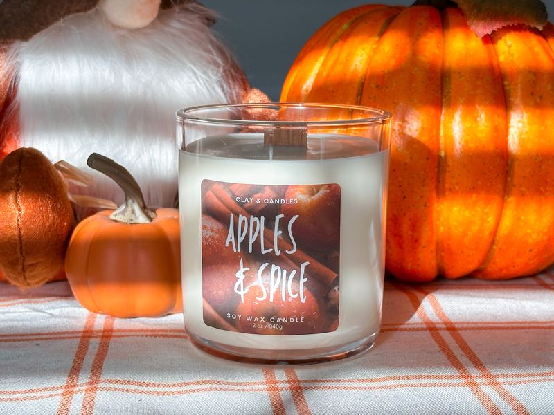 Apples and Spice candle among glowing pumpkins on a plaid runner