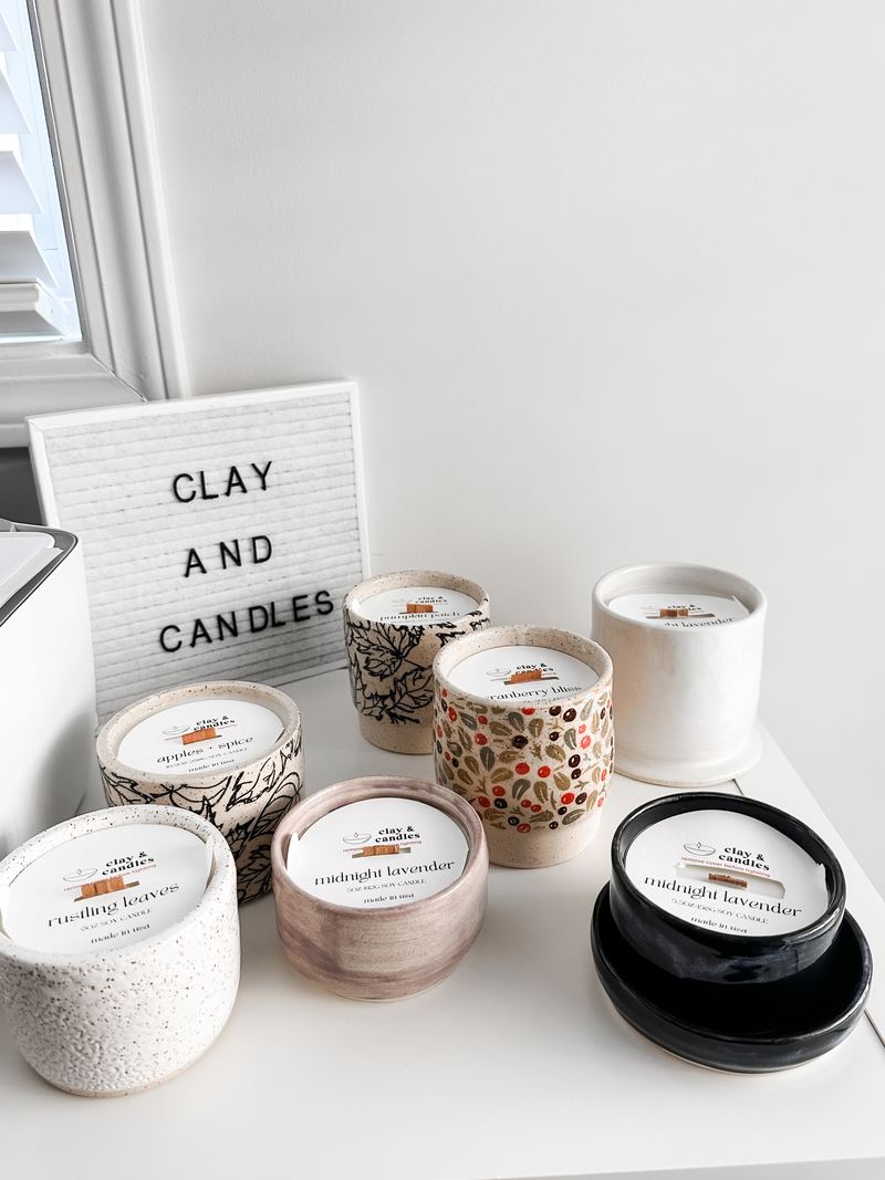 A group of ceramic candles beside a Clay and Candles letter board
