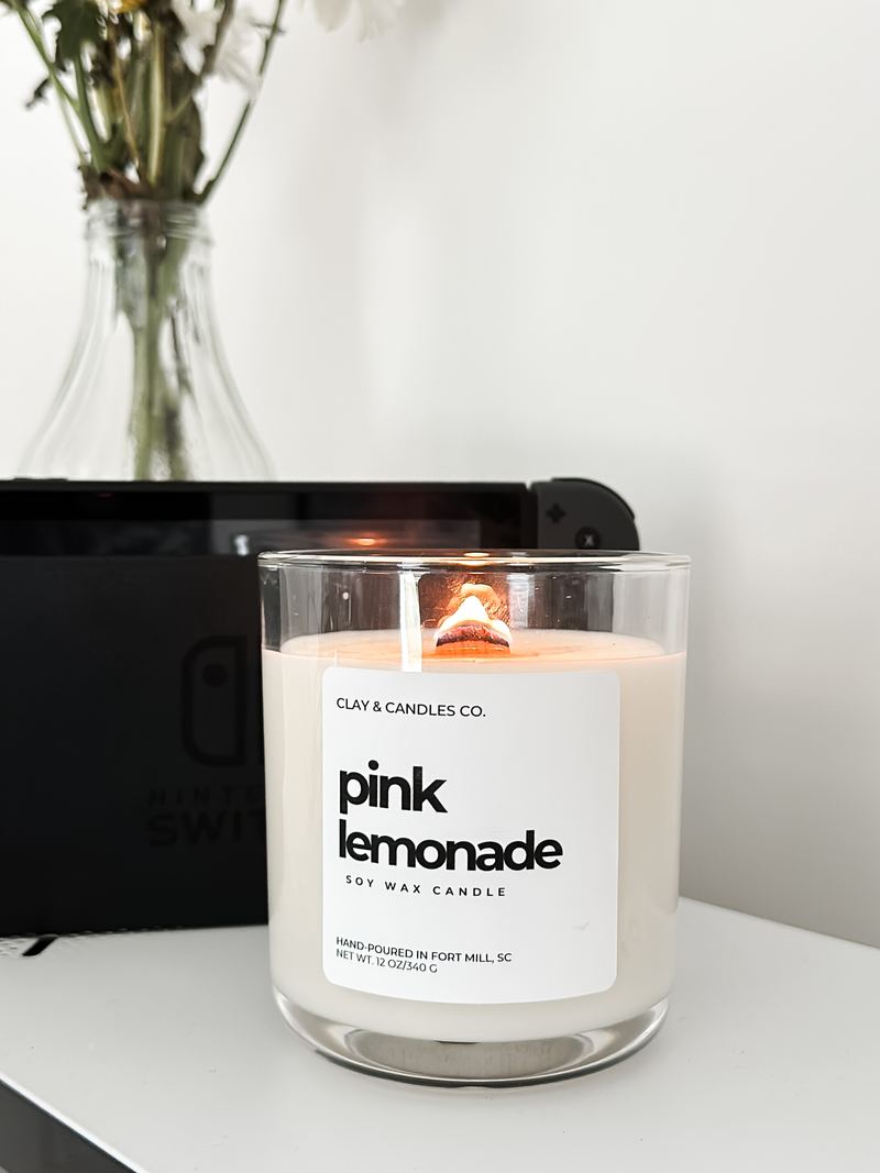 A lit Pink Lemonade soy candle with a crackling wood wick
