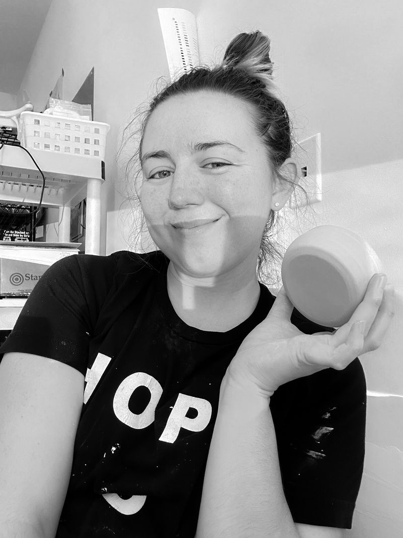 Kassandra Flanders, the maker behind Clay and Candles, smiling and holding one of her candles